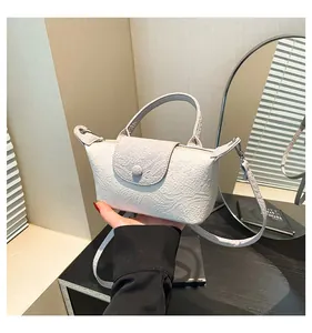 Close-up of light grey mini handbag with snakeskin pattern and trapezoidal structure