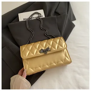 Close-up of golden quilted mini bag with metallic chain strap and stylish buckle lock