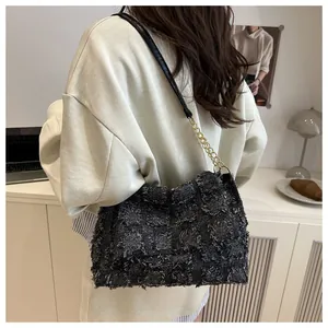 Detail of dark grey tweed crossbody bag with textured grid and gold chain strap