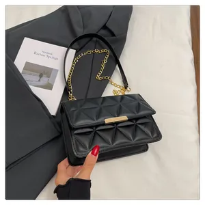 Detail of triangular quilted pattern on black leather bag with gold buckle and chain