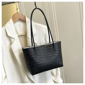 Detail of black woven tote bag showing the luxury leather texture and crossbody strap