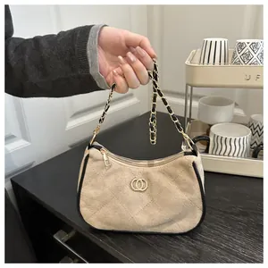Detail view of beige quilted faux suede handbag with gold double-ring buckle and chain strap