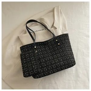 Gros plan sur le sac cabas en tweed noir et doré avec sa petite pochette assortie