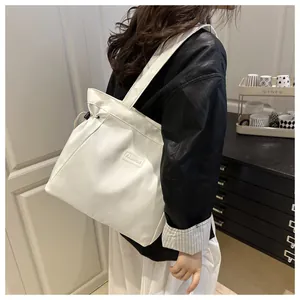 Detail of white nylon tote bag with drawstring closure and Fashion label on the side