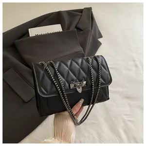 Detail of black quilted leather shoulder bag with dark metal chain and rivet lock buckle