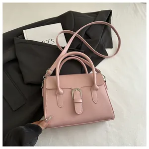 Detail shot of a light pink square handbag with top handles and adjustable shoulder strap