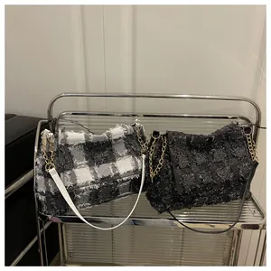 Detail of tweed checkered and black shoulder bags with golden chain and straps