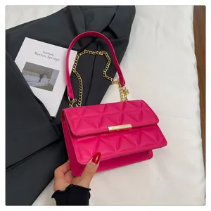 Close-up of fuchsia quilted handbag with gold metal lock and elegant chain strap