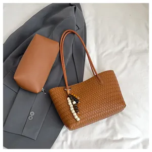 Close-up of brown woven leather tote with inner pouch and wooden bead charm detail