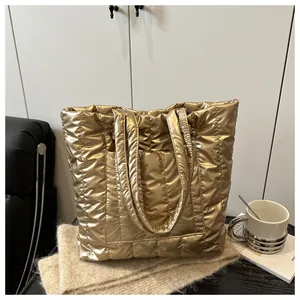 Detail of a large quilted gold tote bag featuring metallic waterproof fabric and wide handles
