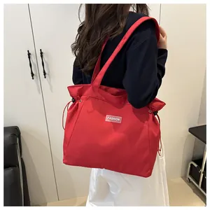 Detail of red drawstring nylon tote bag with fashion label and wide shoulder straps