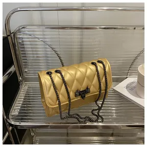 Detail of gold quilted leather bag with black metal chain and unique geometric clasp