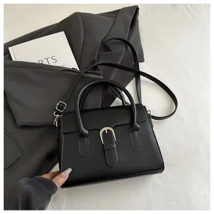 Detail of black leather handbag with silver buckle on grey blazer and white background