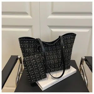 Détail d'un ensemble cabas en tweed noir et doré posé sur une chaise chic
