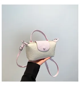 Detail of mini crossbody bag with embossed floral texture and pink contrast flap