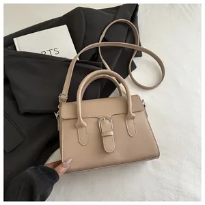 Detail view of beige crossbody bag with top handles and stylish buckle decoration