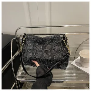 Close-up of textured checkered crossbody bag with gold chain and black leather straps