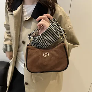 Brown quilted crossbody bag with gold hardware and chain strap on a trench coat
