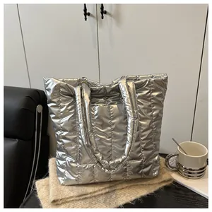 Detail of silver quilted tote bag with metallic finish and padded texture on a knit mat