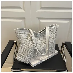 Détail de l'ensemble cabas en tweed et pochette sur fauteuil noir et porte blanche