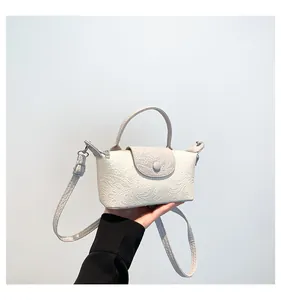 Close-up of white embossed mini crossbody bag with dragon texture and silver hardware