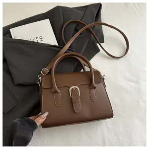 Detailed view of a brown leather bag with a horseshoe buckle on a suit jacket