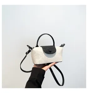 Detail of embossed mini bag featuring black leather flap and contrast top handle