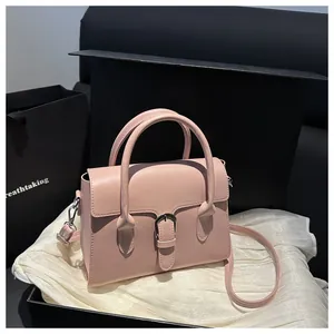Detail of cherry pink trapezoid handbag with leather buckle on white silk background
