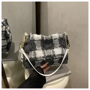 Detailed view of plaid crossbody bag with frayed edges and metallic chain strap
