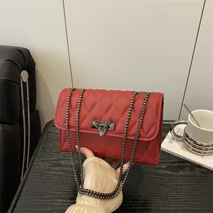 Elegant red quilted leather crossbody bag with metal chain strap on a wooden table