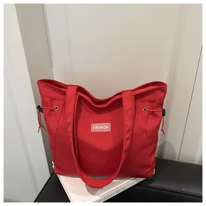 Detail of red nylon tote bag with Fashion label and functional red side drawstrings