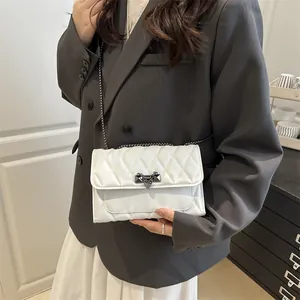 White quilted crossbody bag with metal chain strap worn with a professional grey suit