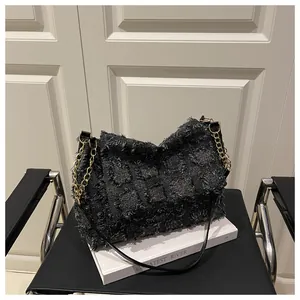 Detail of black checkered plaid shoulder bag with fringe texture and gold chain strap