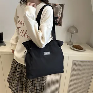 Minimalist black nylon tote bag with drawstring side and FASHION logo on model