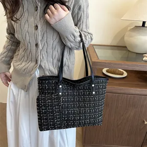 Sac fourre-tout élégant en tweed noir et doré avec pochette assortie dans un décor chic