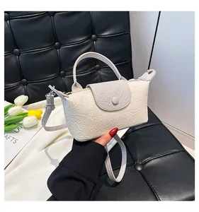 Detailed view of two-tone cream and grey crossbody bag with embossed texture and metal clasp