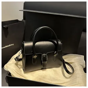 Detail of black crossbody bag with silver buckle on silk background and gift box