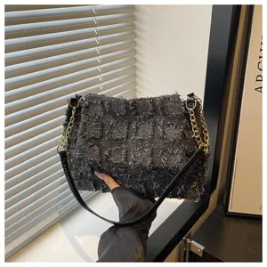 Detail of grey checkered tweed handbag with distressed edges and gold chain link strap