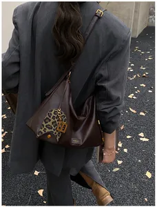 Detail of dark brown leather hobo bag featuring leopard print pocket and gold B pendant
