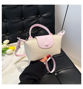 Detail of pink and beige crossbody bag featuring embossed dragon skin texture and round buckle