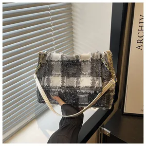 Detailed shot of checkered tweed bag featuring raw fringe edges and gold chain strap