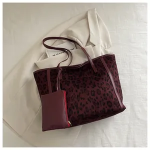 Detail of red leopard print tote bag with matching pouch on beige blazer background