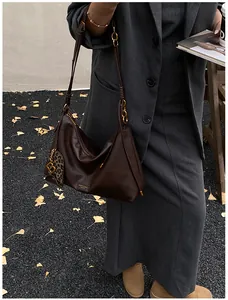 Close-up of deep brown leather tote with gold chain strap and leopard heart charm detail