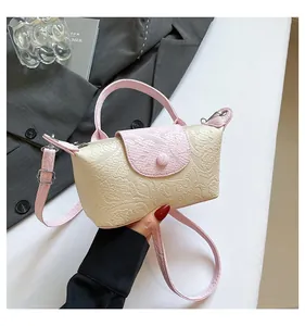 Detailed view of the embossed floral texture and contrast handle on the crossbody bag