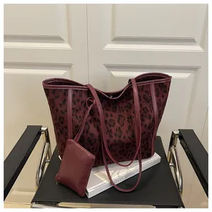 Close-up of leopard print tote bag and matching pouch on a black metal chair