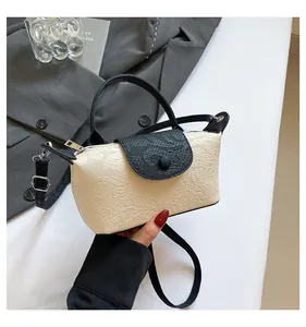 Detail of cream crossbody bag with black handles and embossed floral texture