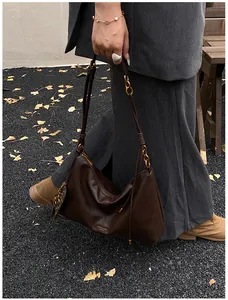 Detailed view of brown leather handbag with gold chain and leopard print charm accessory