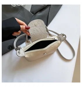 Detailed close-up of floral embossed texture and dual closure on ivory crossbody bag