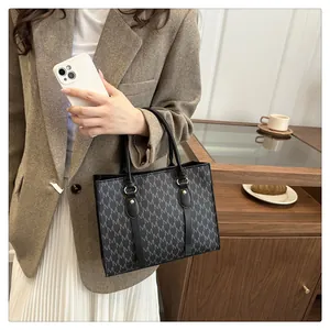 Close-up of classic tote bag with M-letter monogram print and sturdy black handles