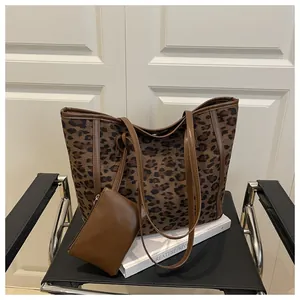Detail of leopard print tote bag set featuring canvas texture and brown leather pouch